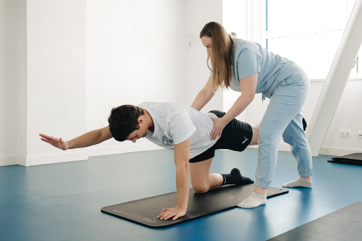 Uma fisioterapeuta guia os exercícios de um paciente em um ginásio, representando a avaliação profissional da mobilidade.
