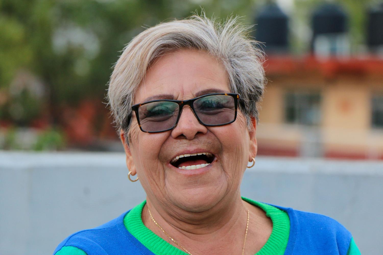 Retrato cercano de uma mulher maior rindo genuinamente ao ar livre, representando a saúde mental e o bem-estar emocional na terceira idade.