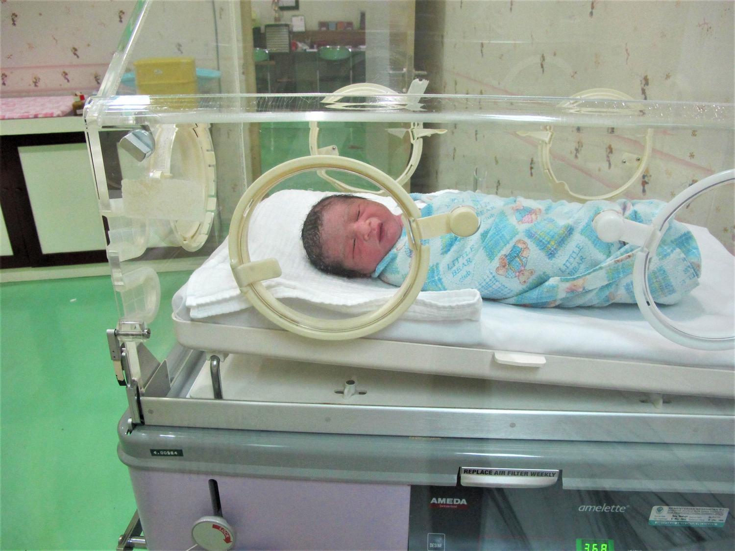 Primer plano de un bebé prematuro descansando en una incubadora hospitalaria.