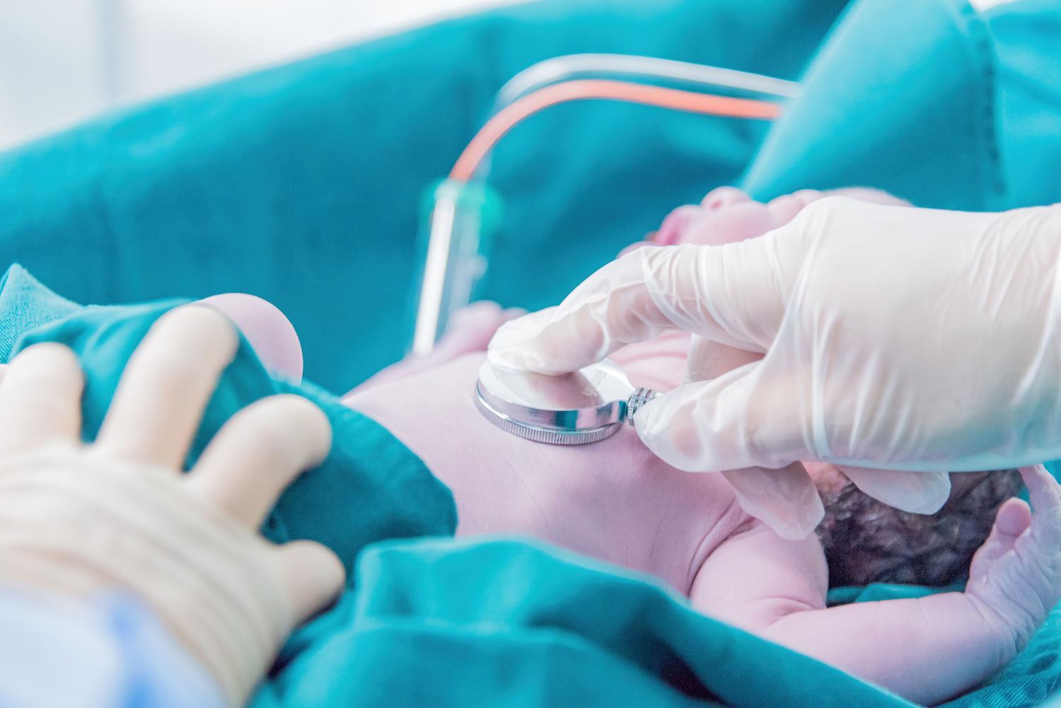 Profesional médico examinando a un recién nacido con un estetoscopio en el hospital.