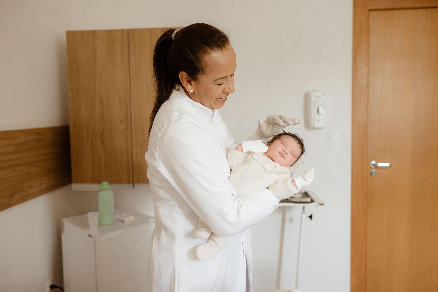 Especialista en neonatología sosteniendo con cuidado a un recién nacido en una habitación de hospital.