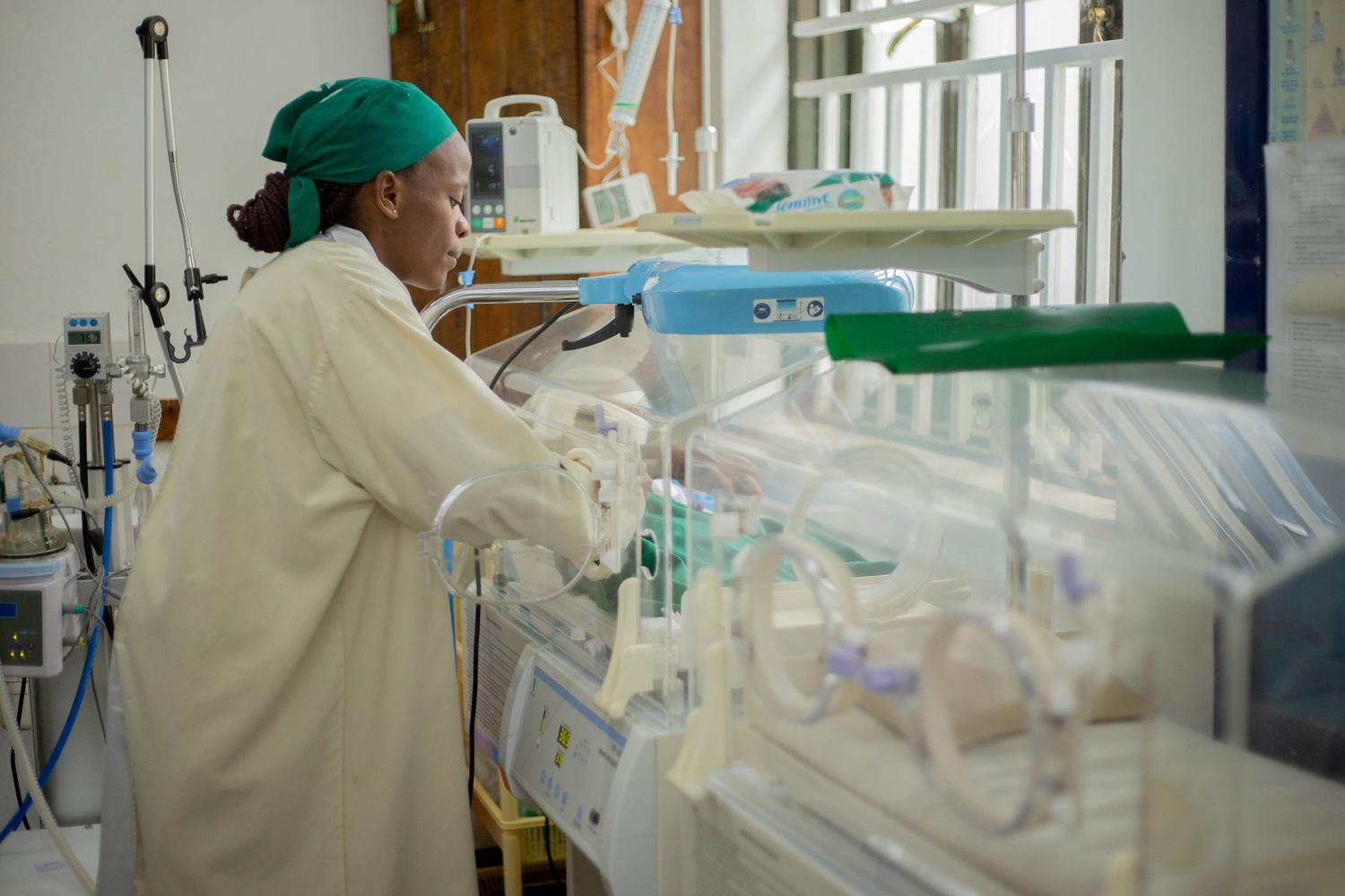 Médico atendiendo a recién nacidos en una incubadora en una unidad de neonatología hospitalaria.