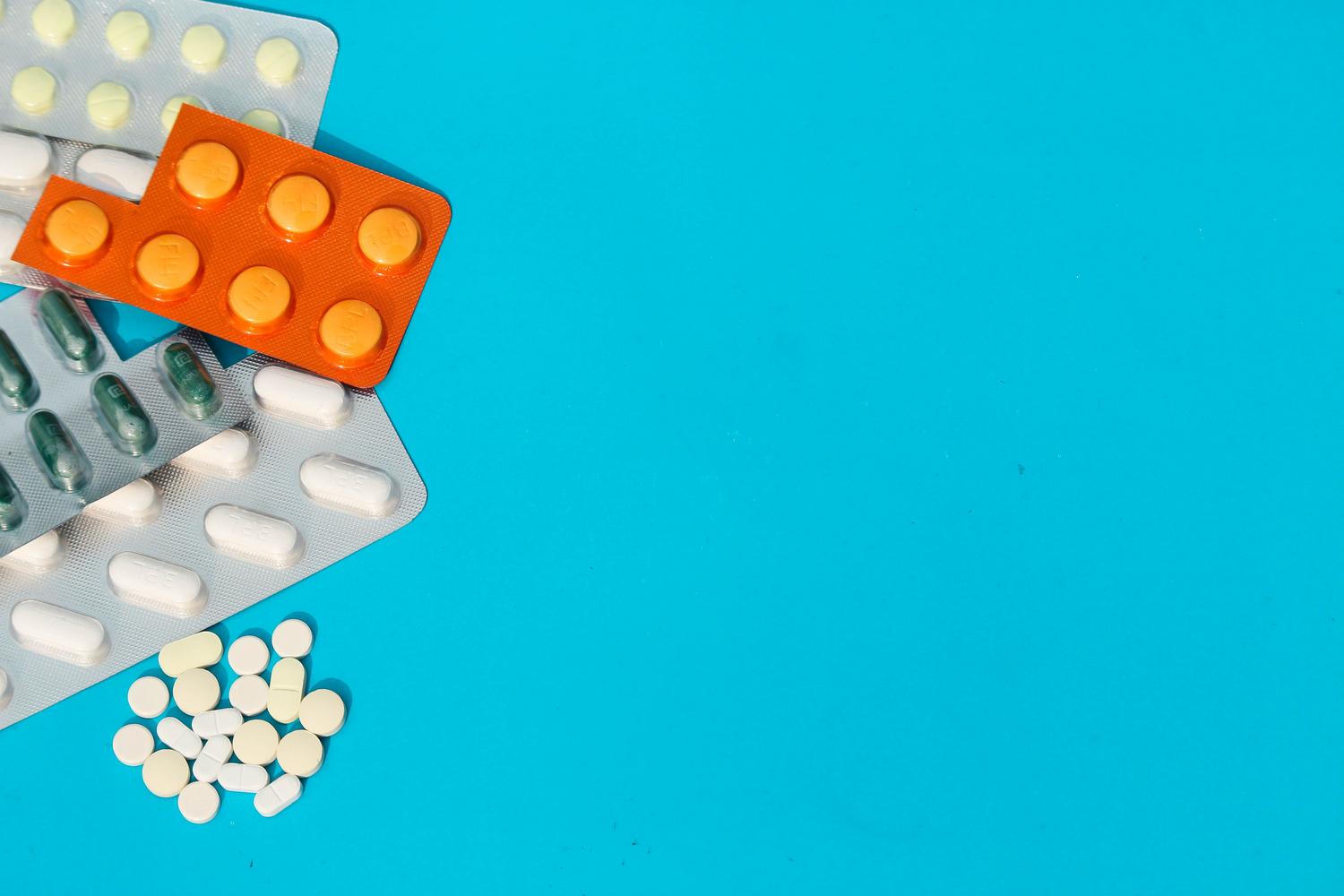 Variedad de comprimidos y blísteres sobre un fondo azul, resaltando las diferentes formas farmacéuticas del medicamento.