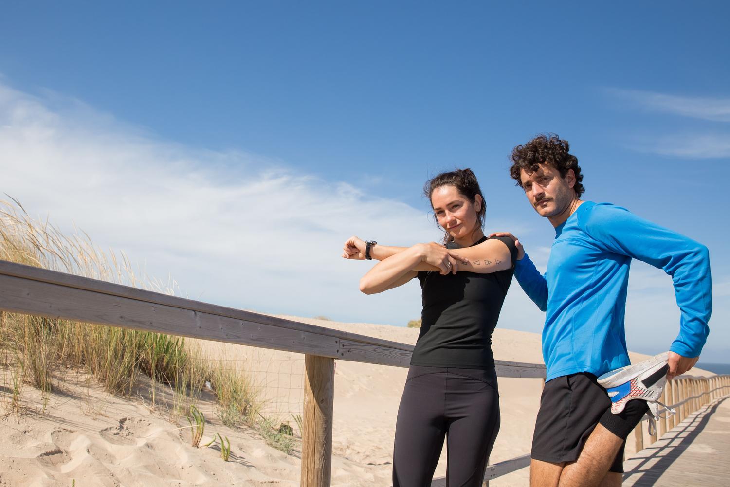 Pareja haciendo ejercicios de flexibilidad y estiramientos en un paseo marítimo costero Pareja haciendo ejercicios de flexibilidad y estiramientos en un paseo marítimo costero