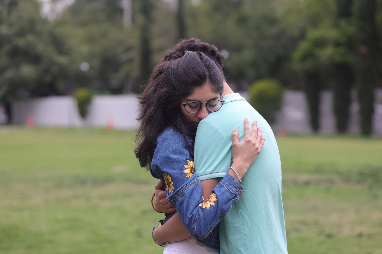 Um casal se abraçando afetuosamente em um parque, refletindo a segurança, a confiança e o apoio mútuo em um relacionamento sentimental.