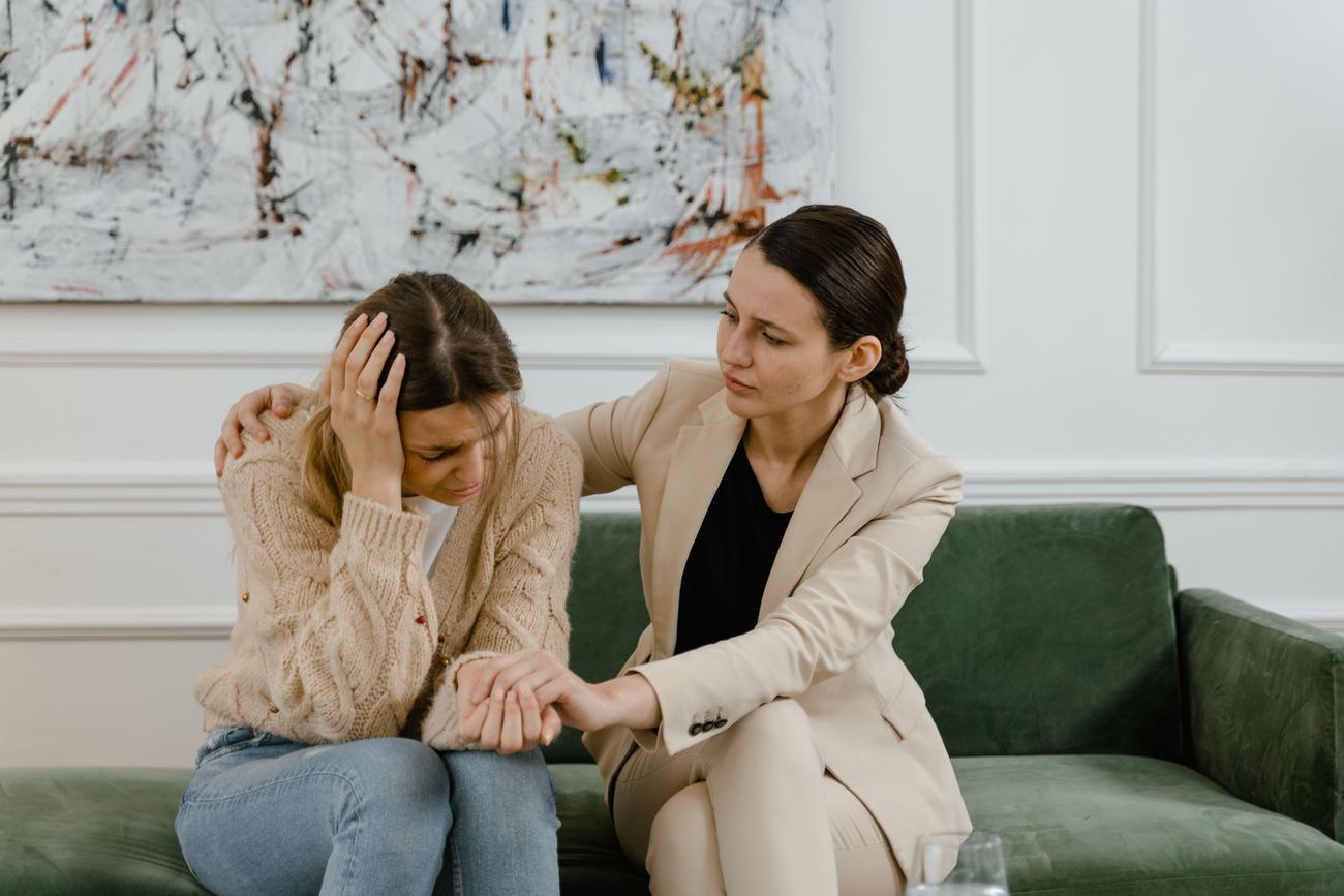 Uma profissional da saúde mental ouvindo ativamente e dando suporte emocional a uma mulher em um espaço seguro e acolhedor.