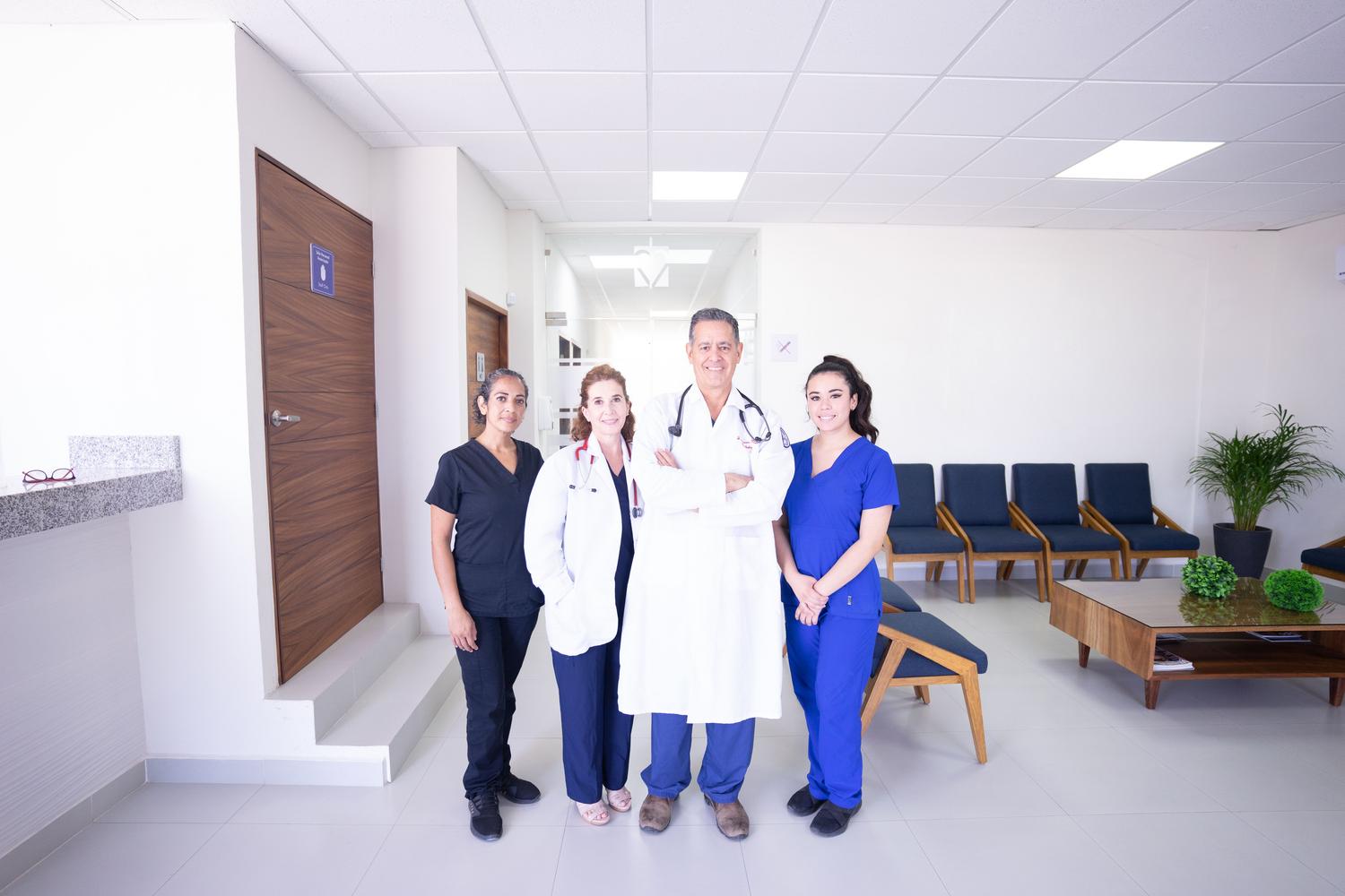 Equipo multidisciplinar de enfermería y médicos sonriendo en un entorno hospitalario moderno, representando la cooperación y el compañerismo.
