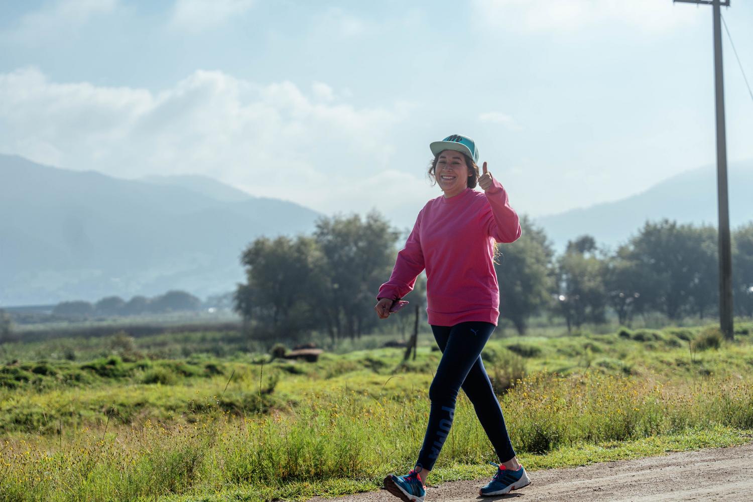 Mujer caminando alegremente por um sendero natural, ilustrando a atividade física recomendada para mejorar a circulação. Mujer caminando alegremente por um sendero natural, ilustrando a atividade física recomendada para mejorar a circulação.