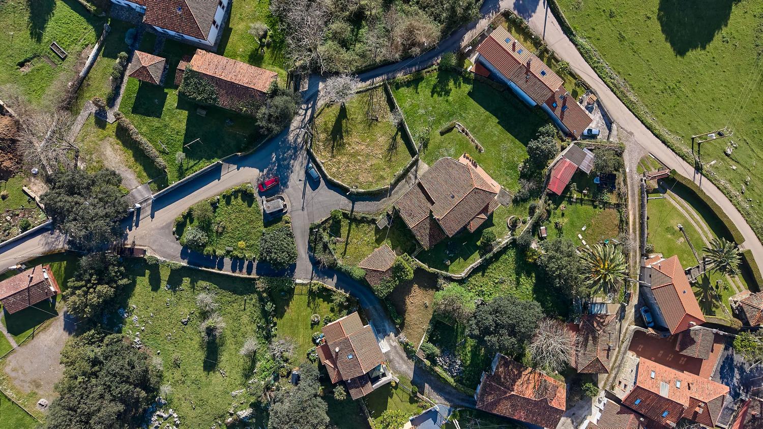 Vista aérea de una aldea rural tradicional en Cantabria con casas de piedra y entorno natural exuberante. Vista aérea de una aldea rural tradicional en Cantabria con casas de piedra y entorno natural exuberante.