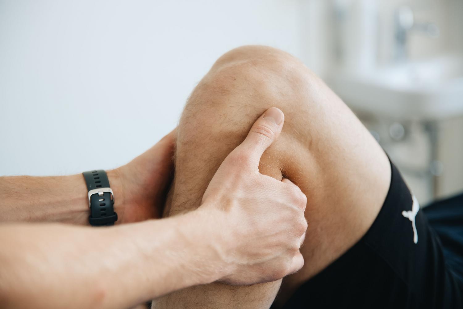 Sesión de fisioterapia donde un profesional realiza un masaje terapéutico en la rodilla de un paciente para mejorar la movilidad y reducir la inflamación.