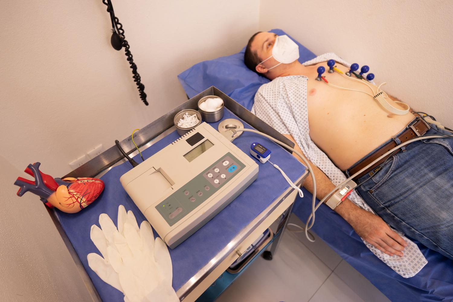 Hombre adulto realizándose un electrocardiograma (ECG) en una clínica, representando el monitoreo del riesgo cardiovascular asociado a la artritis reumatoide sistémica.