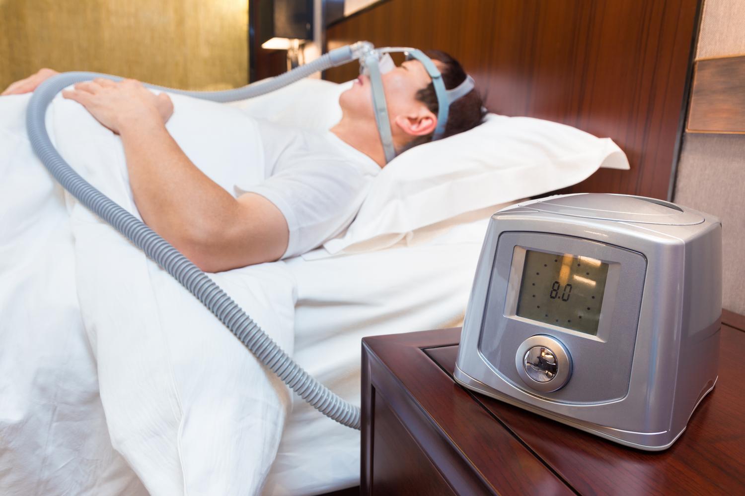 Hombre durmiendo plácidamente utilizando una máquina CPAP, representando la terapia de presión positiva continua para el tratamiento del SAOS.