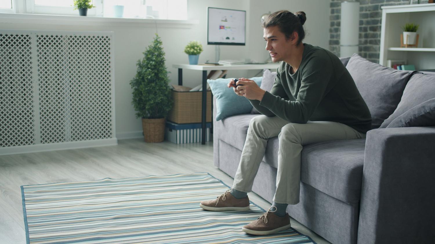 Um jovem sorridente desfrutando de uma sessão de videogames em casa, transmitindo bem-estar emocional e alegria.