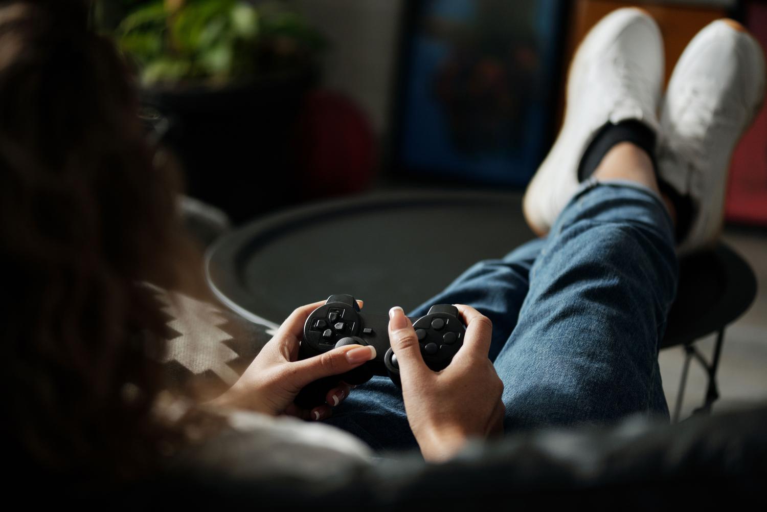 Uma mulher descansando confortavelmente enquanto joga, representando o videogame como um espaço de relaxamento e pausa do estresse diário.