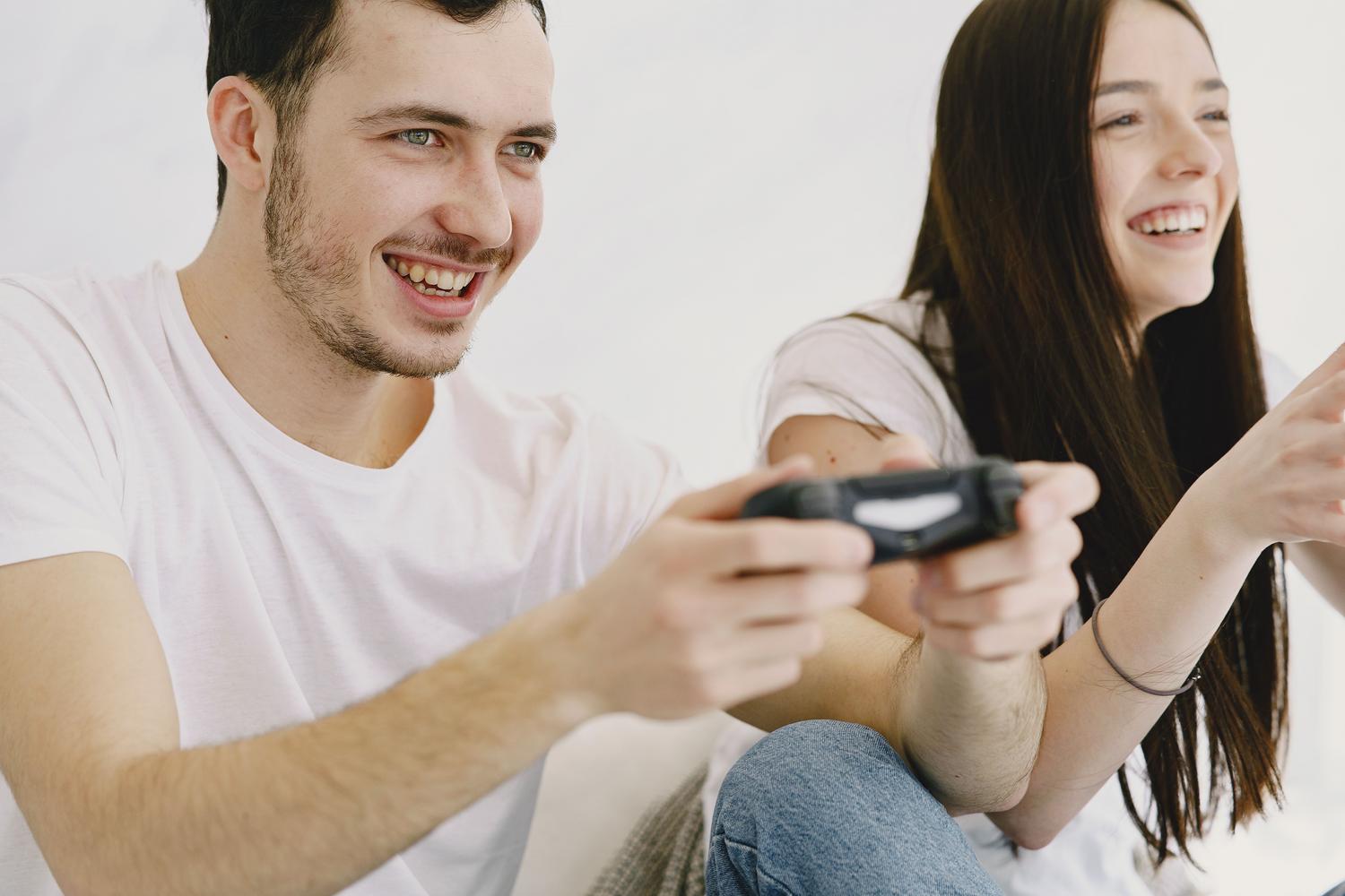 Um casal feliz rindo enquanto joga videogames, destacando a conexão emocional e a socialização.