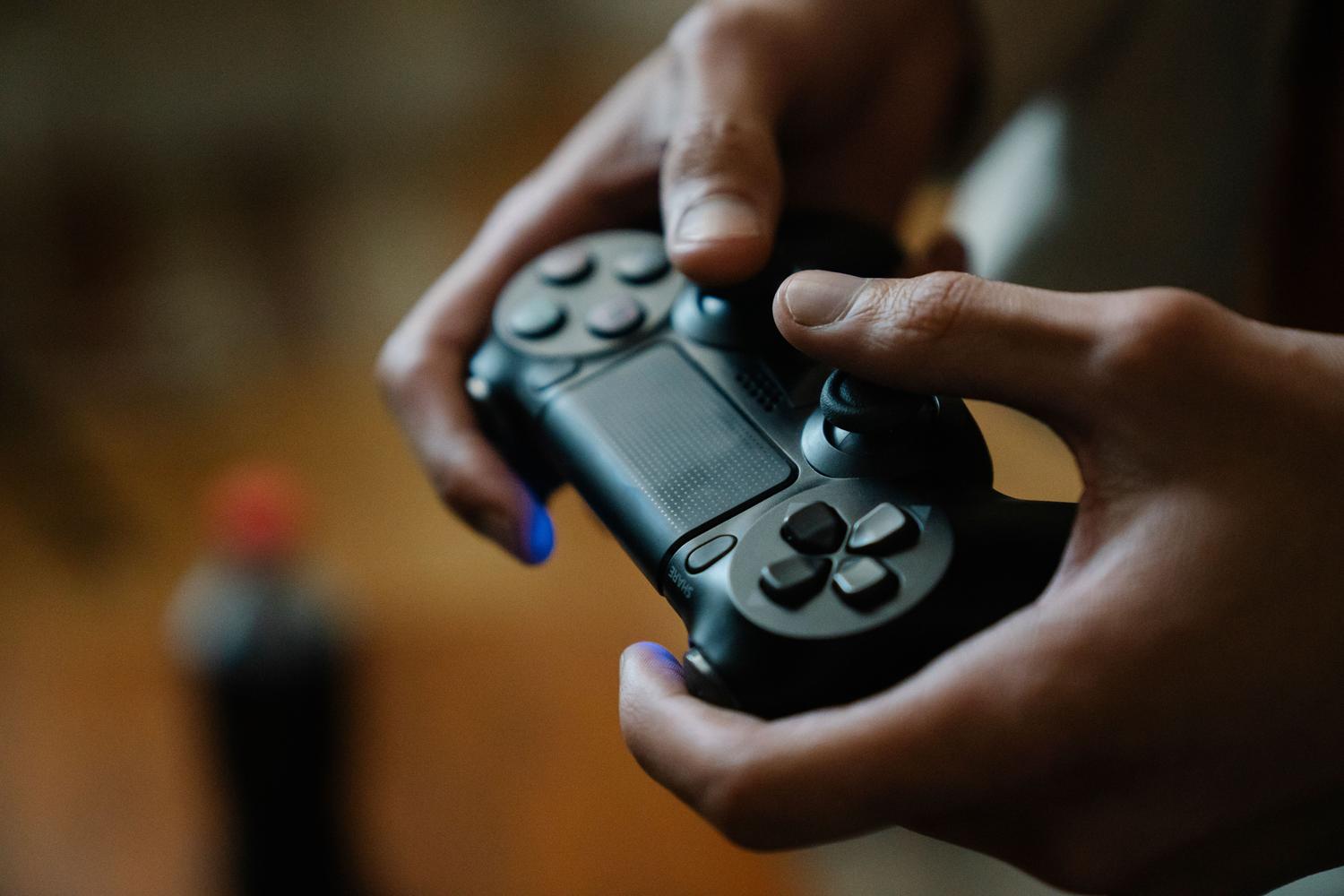 Primeiro plano de mãos manejando um controle de console, simbolizando a imersão e o foco mental que os jogos proporcionam.