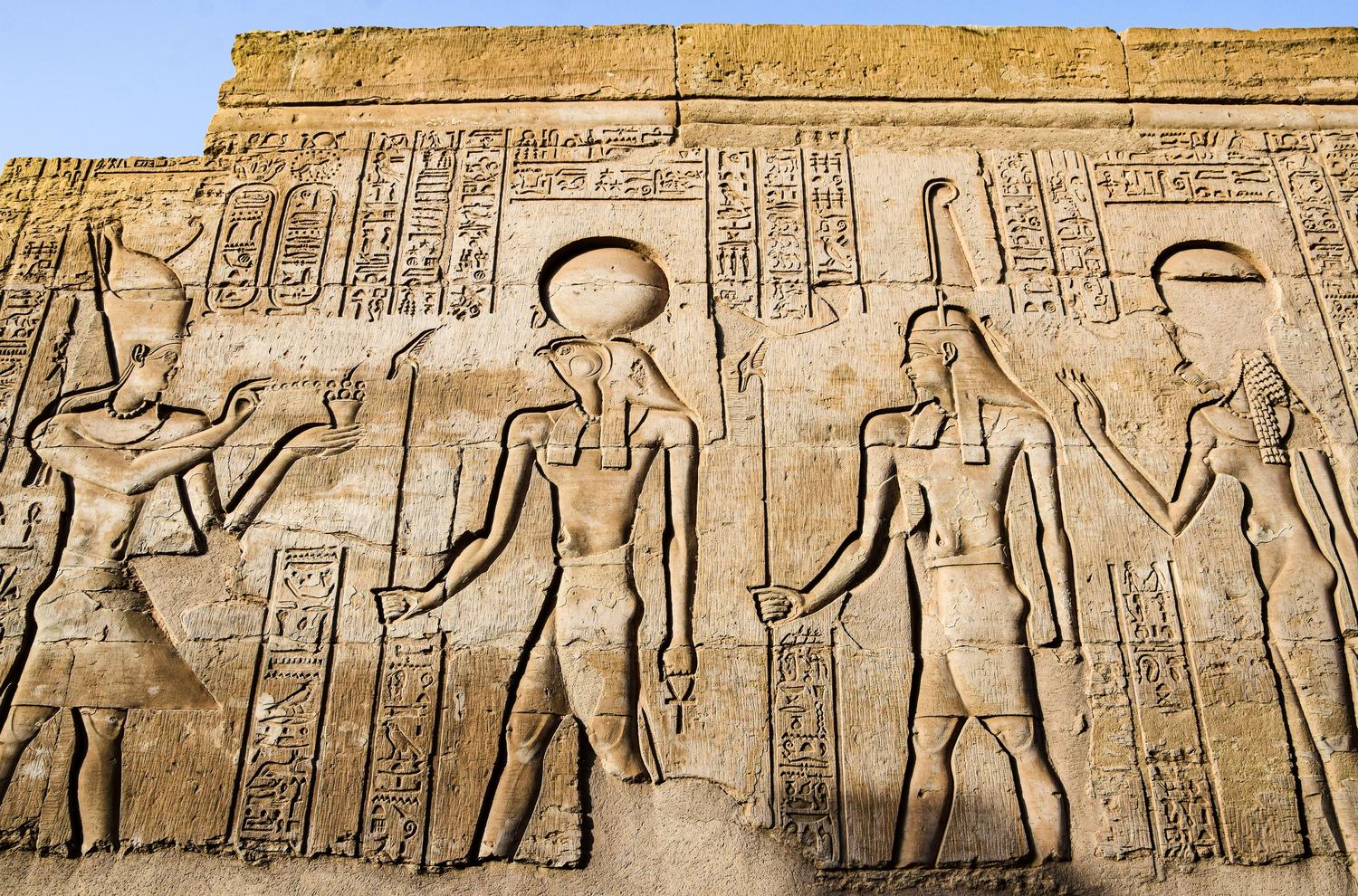 Relieve en la pared de un templo que muestra la interacción entre el faraón y diversas deidades egipcias.