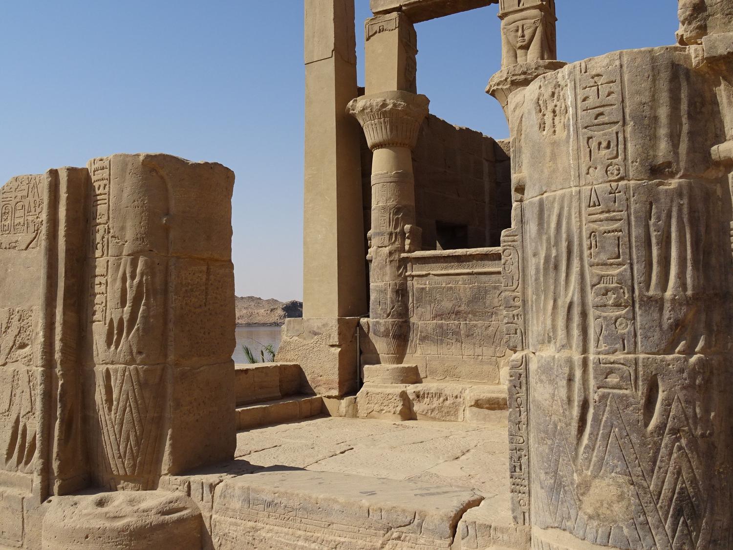 Ruinas de un templo majestuoso del Antiguo Egipto bajo el sol del desierto, con columnas talladas y jeroglíficos.