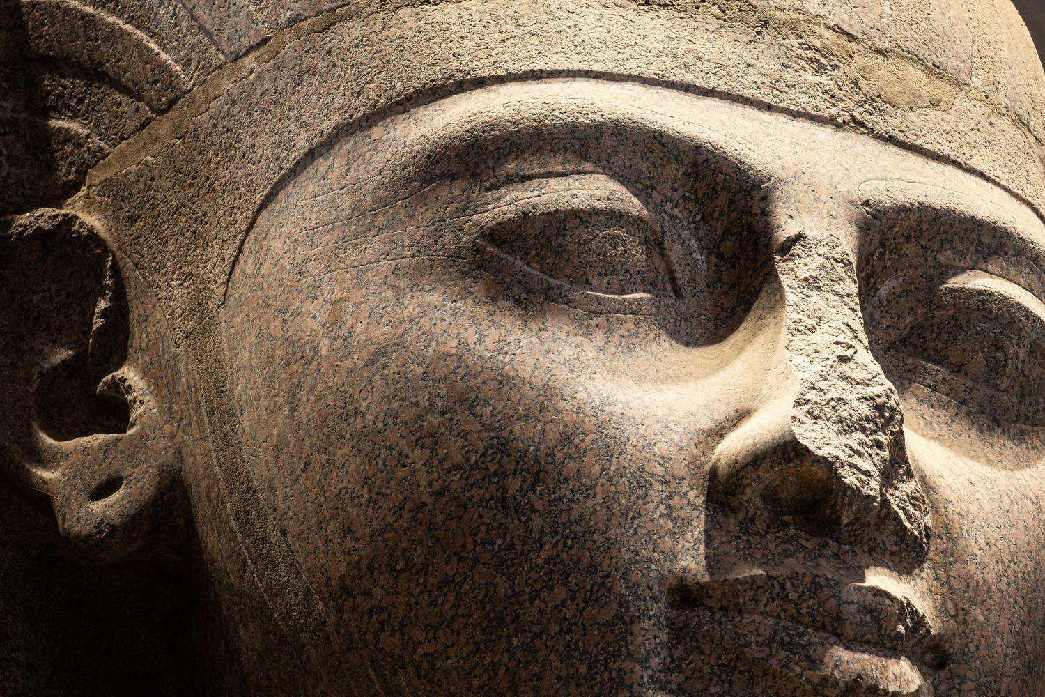 Primer plano detallado de uma estatua de pedra do Antigo Egito, resaltando la serenidad y la maestría escultórica.
