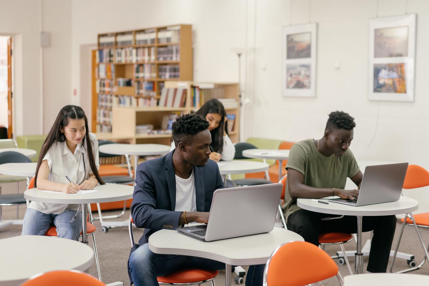 Estudiantes concentrados recopilando información en sus laptops y notas para la elaboración de un trabalho científico.