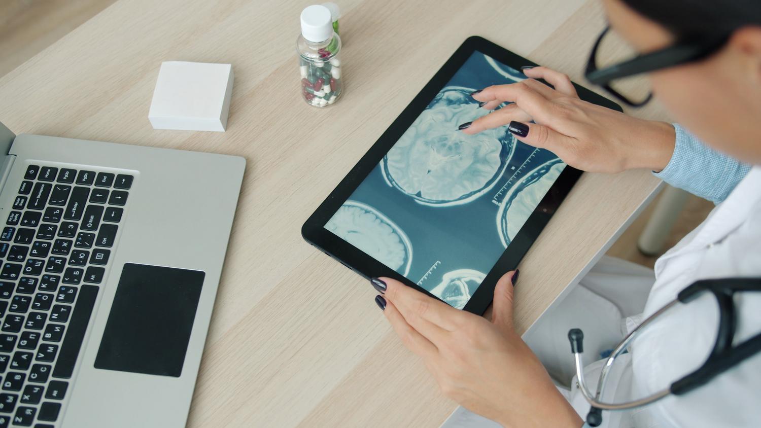 Especialista revisando escaneos cerebrales en una tableta digital para mapear las respuestas cognitivas ante el riesgo y la incertidumbre.