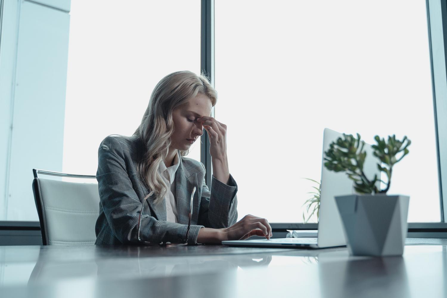 Mujer ejecutiva experimentando estrés laboral, resaltando la importancia de la resiliencia cognitiva en el liderazgo empresarial.