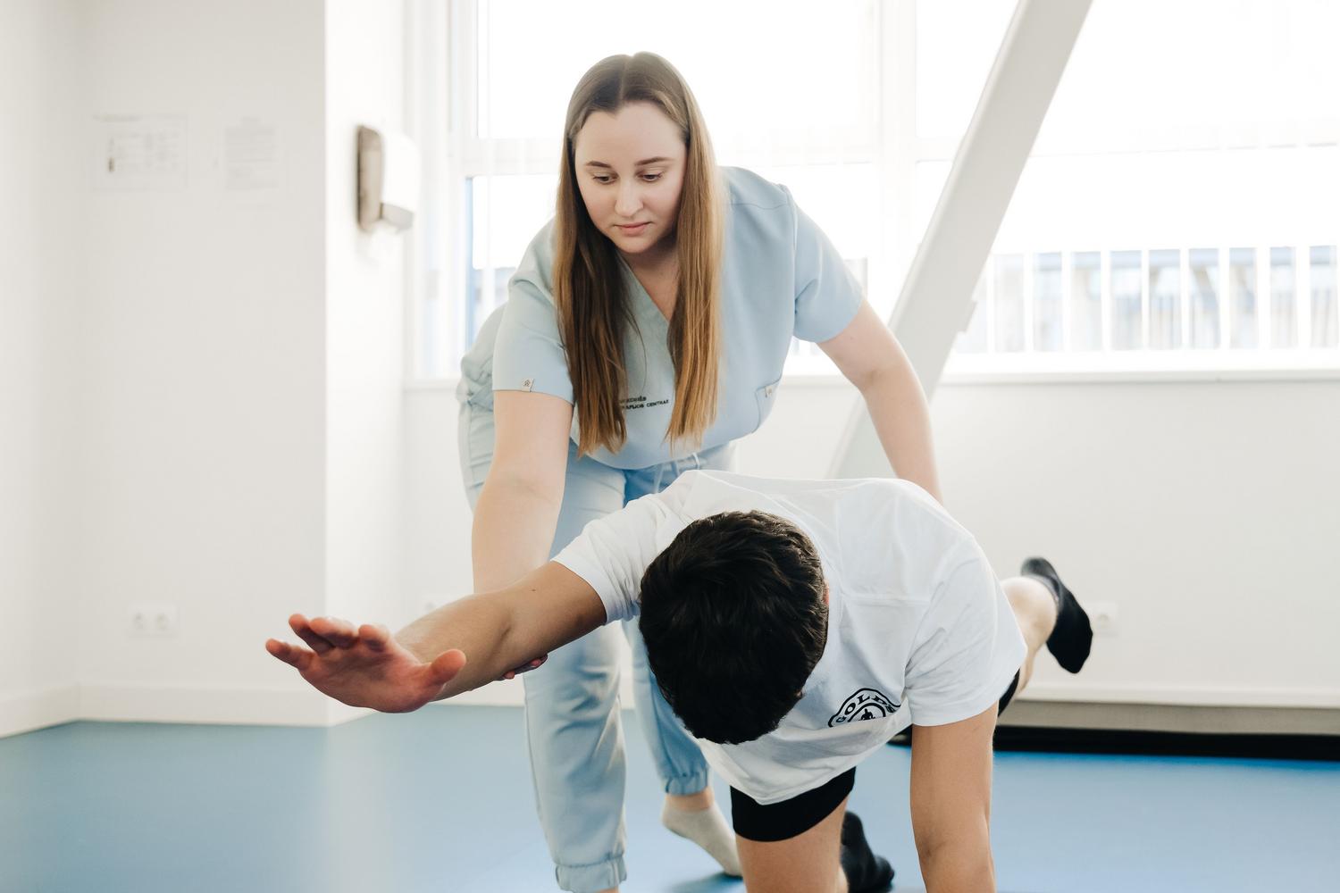 Fisioterapeuta asistiendo a un paciente en ejercicios de estiramiento en una clínica moderna para mejorar la movilidad y reducir la espasticidad.