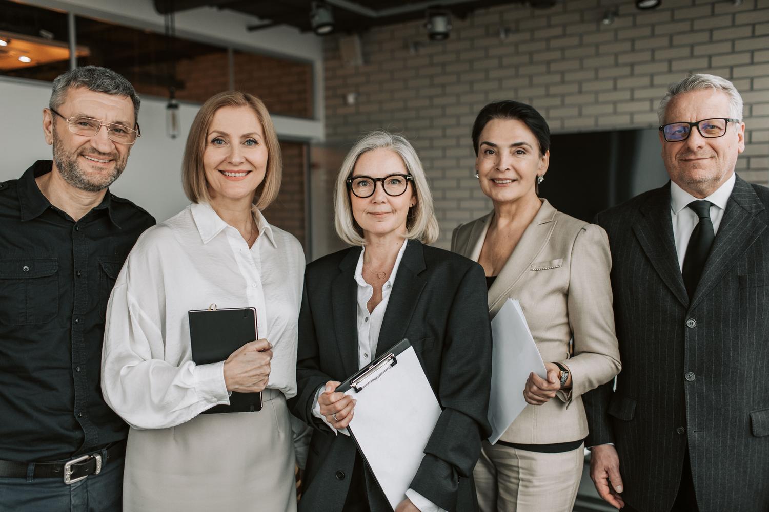 Un equipo diverso de ejecutivos experimentados posando con confianza en una oficina moderna, representando la cúpula ou a parte superior da pirámide organizacional.