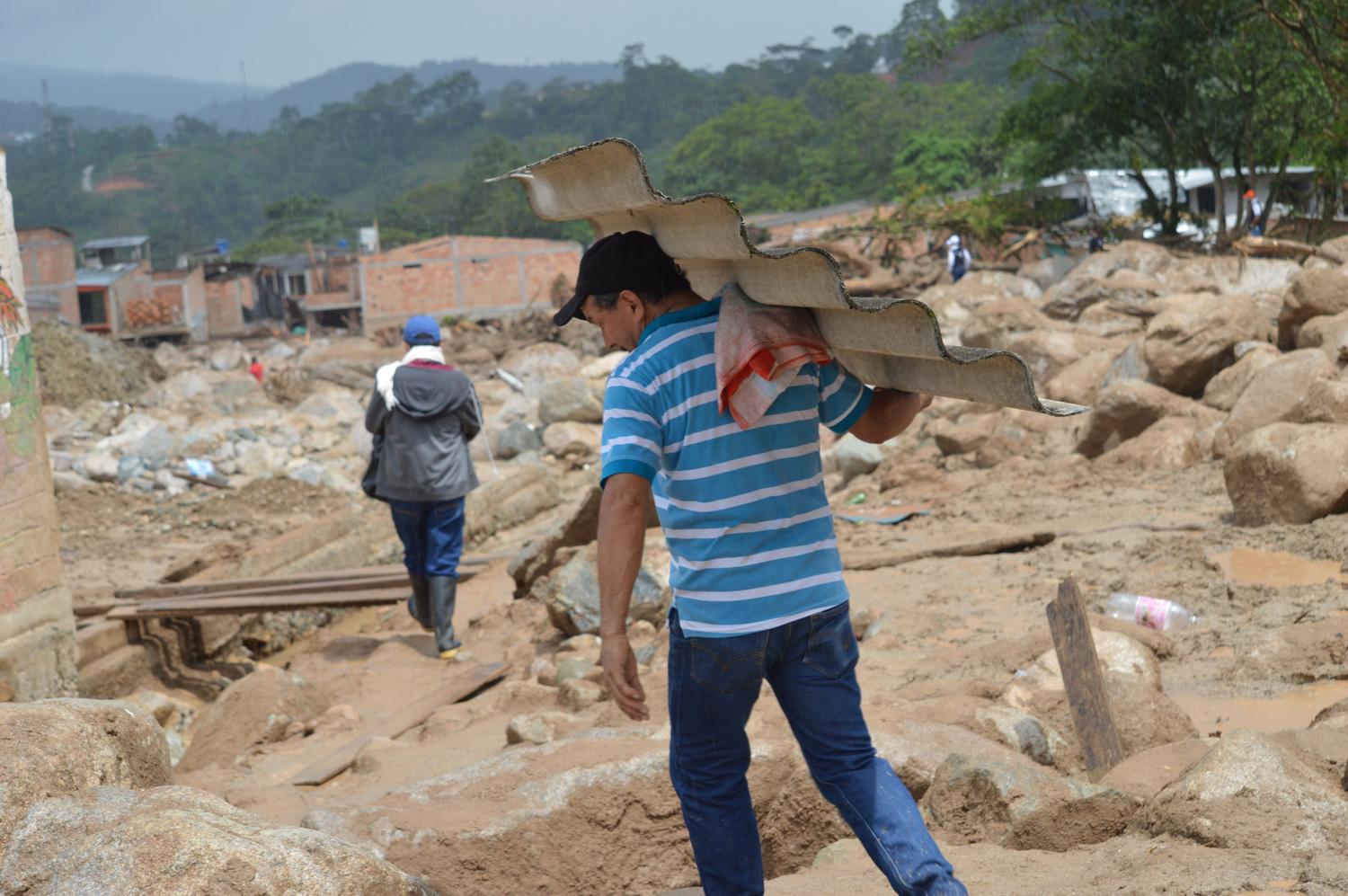 Un hombre trabalha en la reconstrucción de su hogar tras un desastre natural, representando la resiliencia humana.