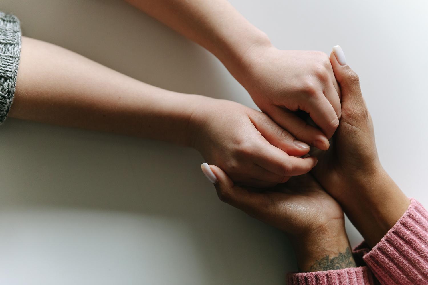 Varias personas entrelazan sus manos simbolizando una red de apoio comunitario y solidaridad.