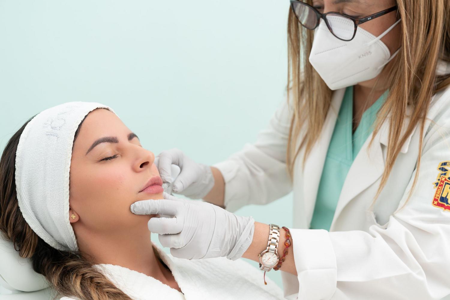 Médico realizando un tratamiento estético facial en una clínica, ejemplificando la vocación y el detalle artístico de la cirugía cosmética.