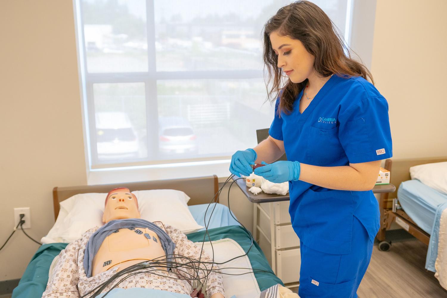 Estudiante de medicina practicando procedimientos en un maniquí de entrenamiento en un laboratorio de simulación clínica.