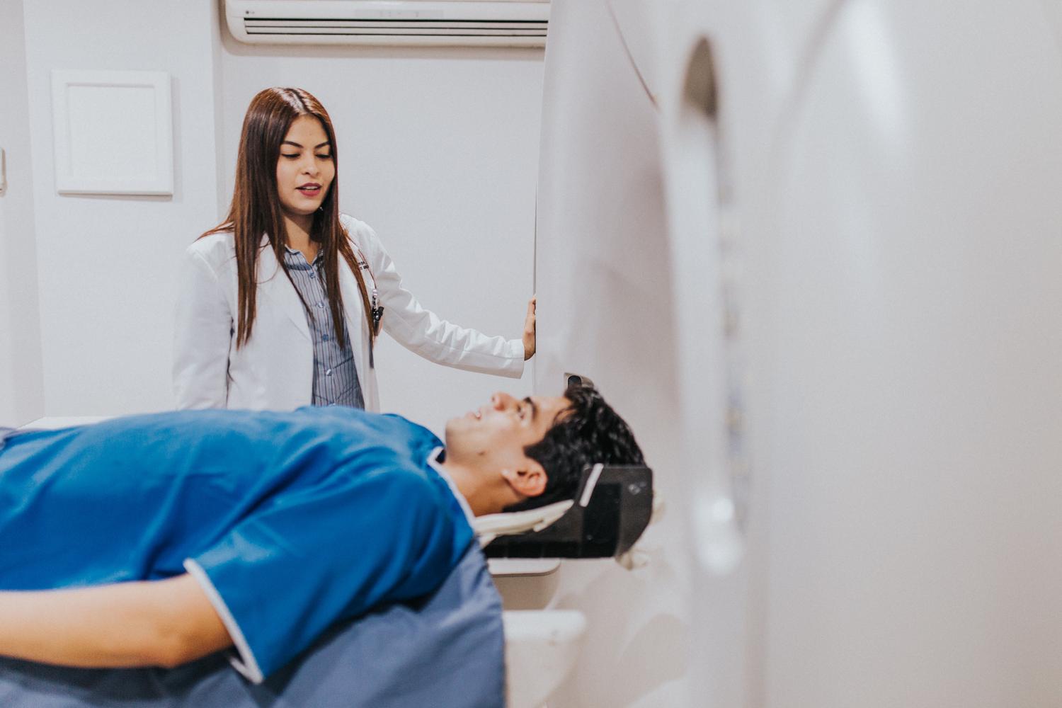 Interacción entre médico y paciente junto a una máquina de resonancia magnética, destacando la medicina no invasiva