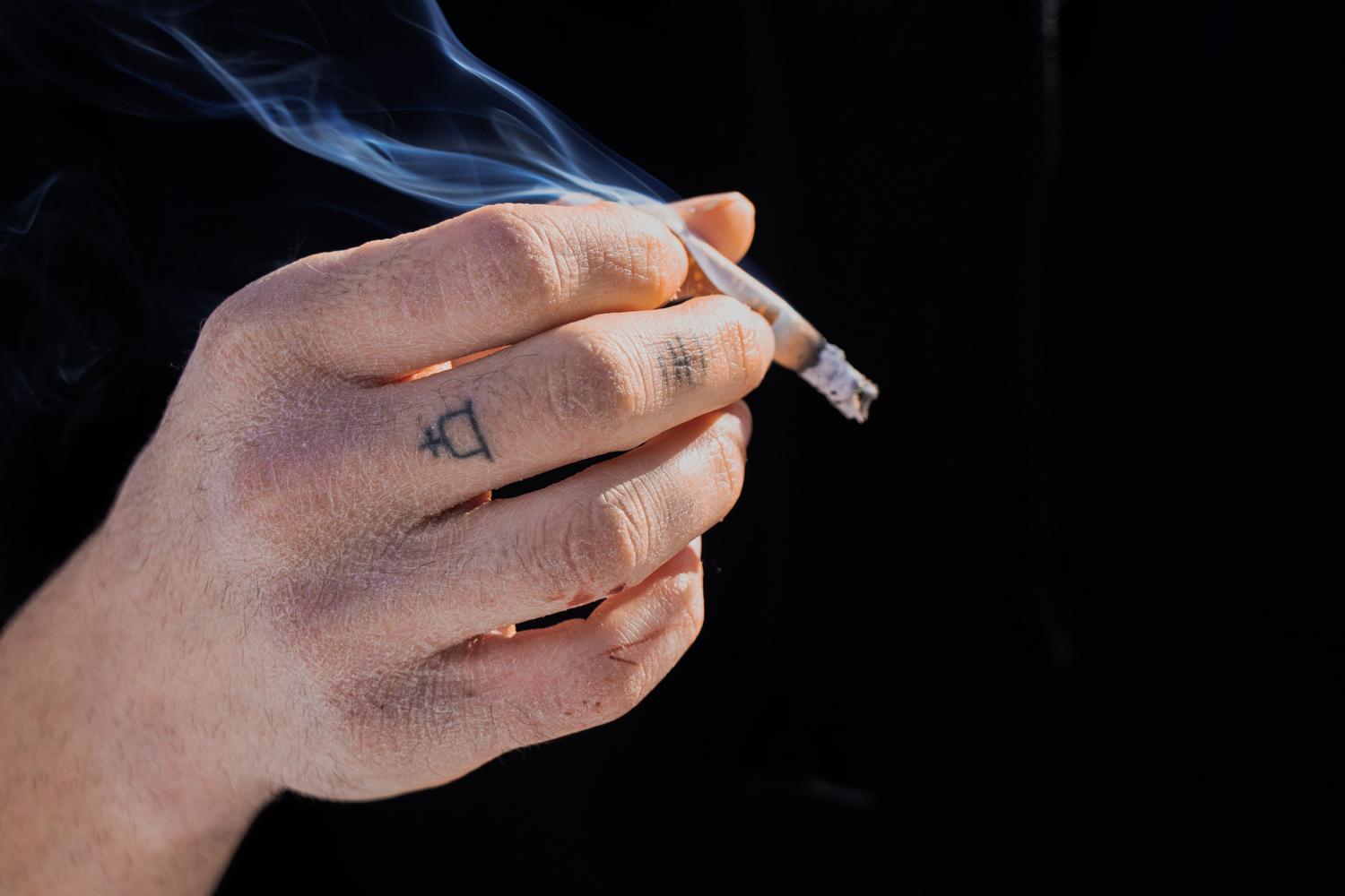Primer plano de una mano sosteniendo un cigarrillo tradicional encendido, representando el hábito del tabaco que se desea abandonar.