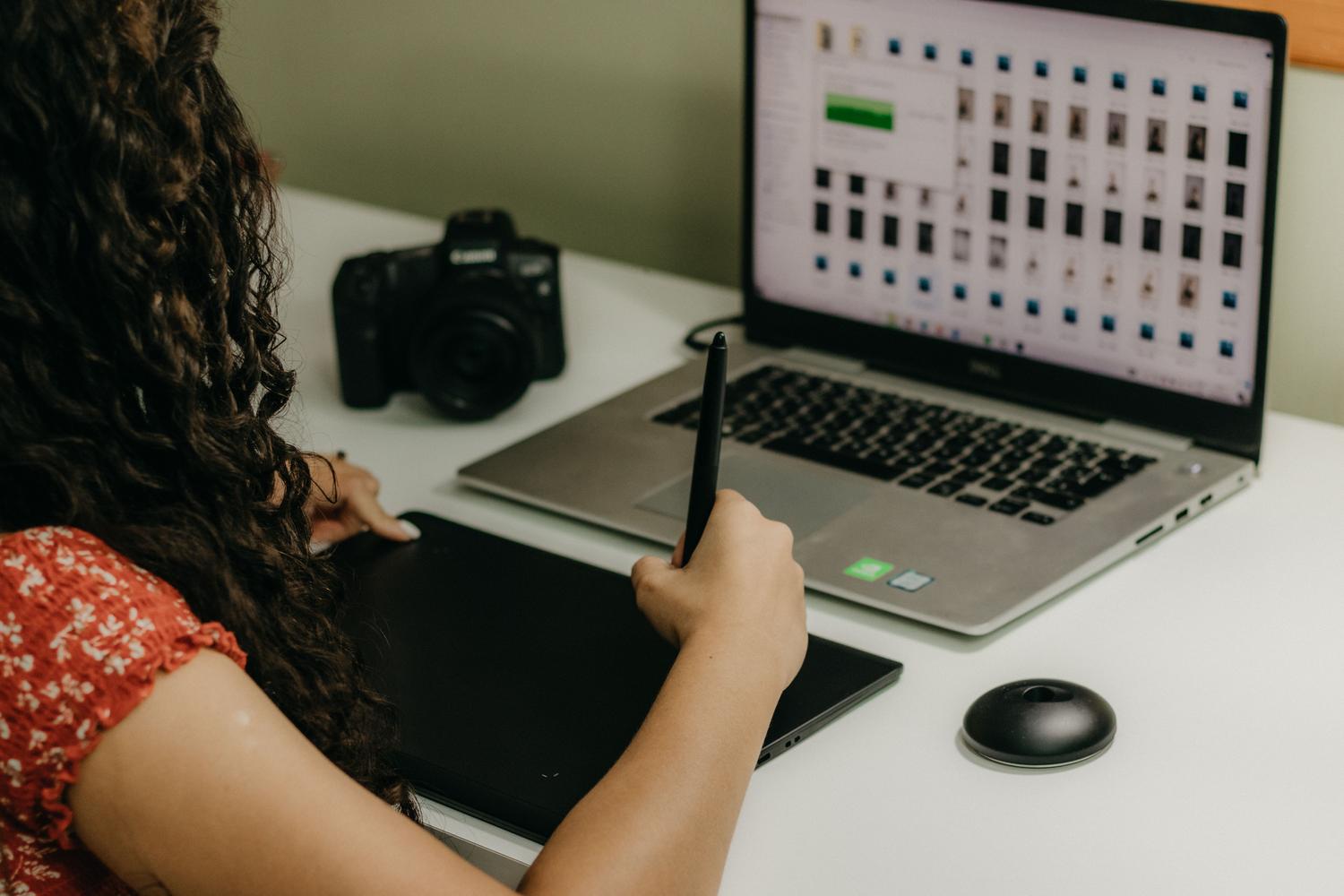 Creador de contenido digital utilizando una tableta gráfica y laptop para la edición técnica de imágenes.