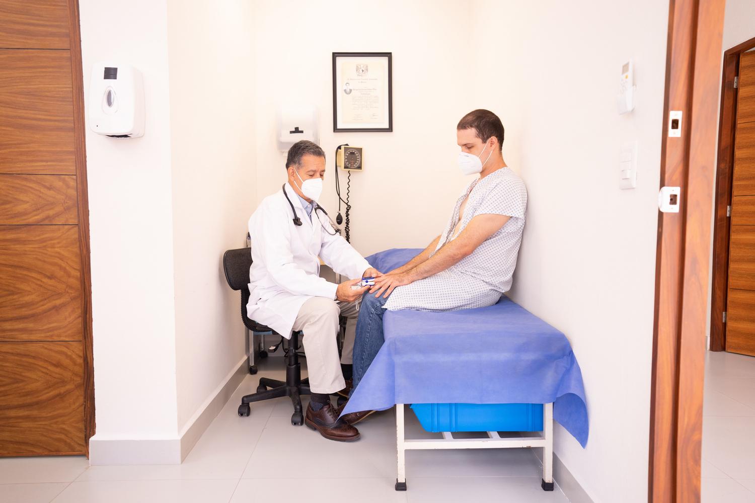 Médico profesional revisando las constantes vitales de un paciente en clínica, simbolizando el seguimiento médico especializado.
