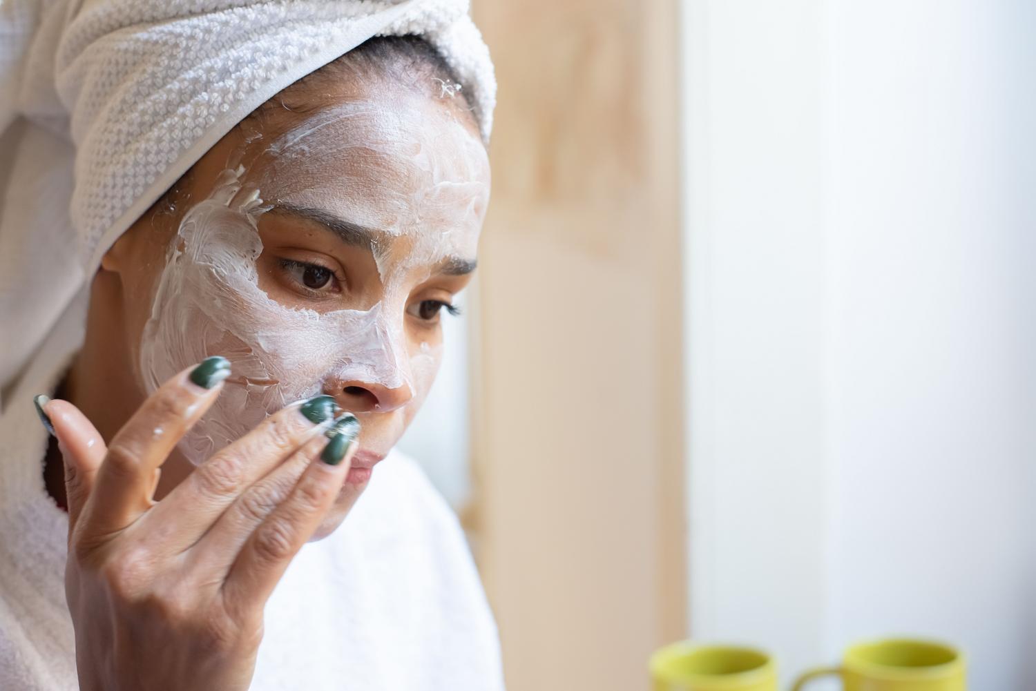 Mujer aplicando crema hidratante nutritiva para restaurar la barrera lipídica de la piel seca.