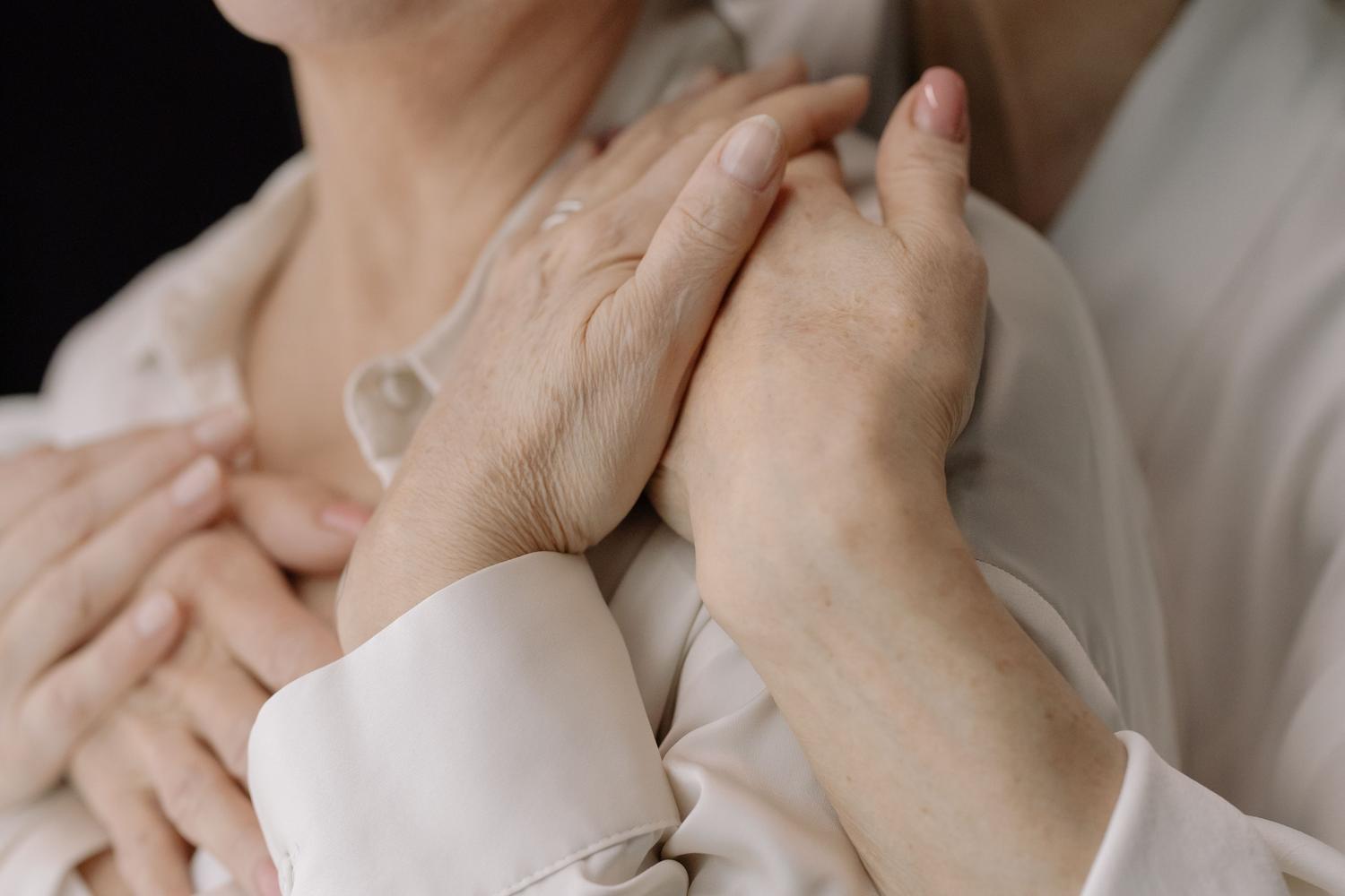 Detalle de manos entrelazadas de personas mayores, simbolizando la conexión, el amor y la fragilidad humana.