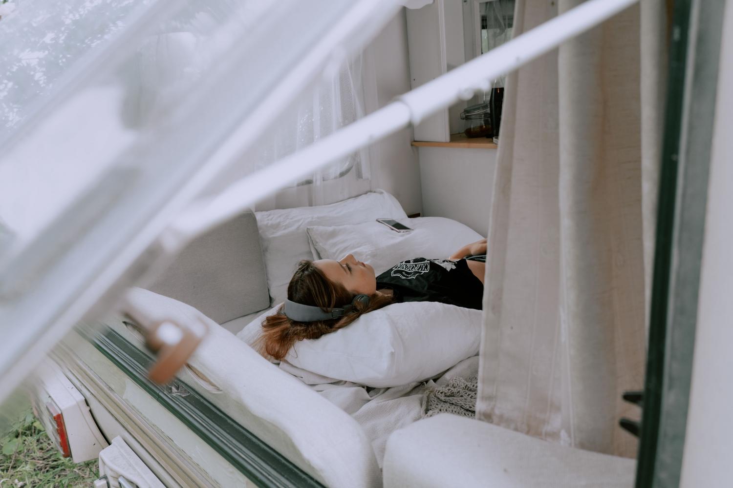 Mujer relajándose en una furgoneta camper escuchando música, ilustrando la importancia de romper la monotonía.