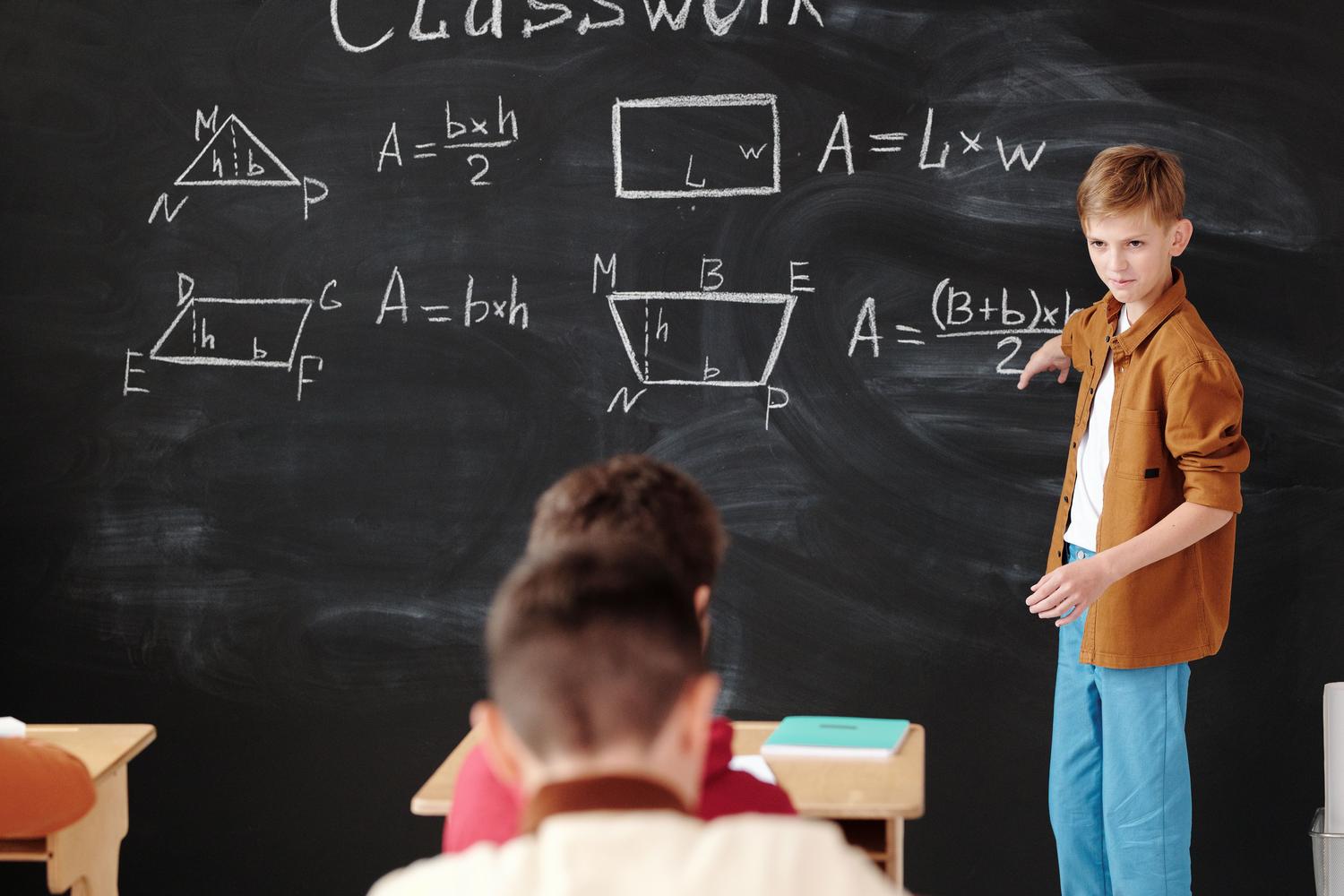 Estudiante joven explicando fórmulas de geometría en una pizarra, representando el aprendizaje activo y el protagonismo del alumno.