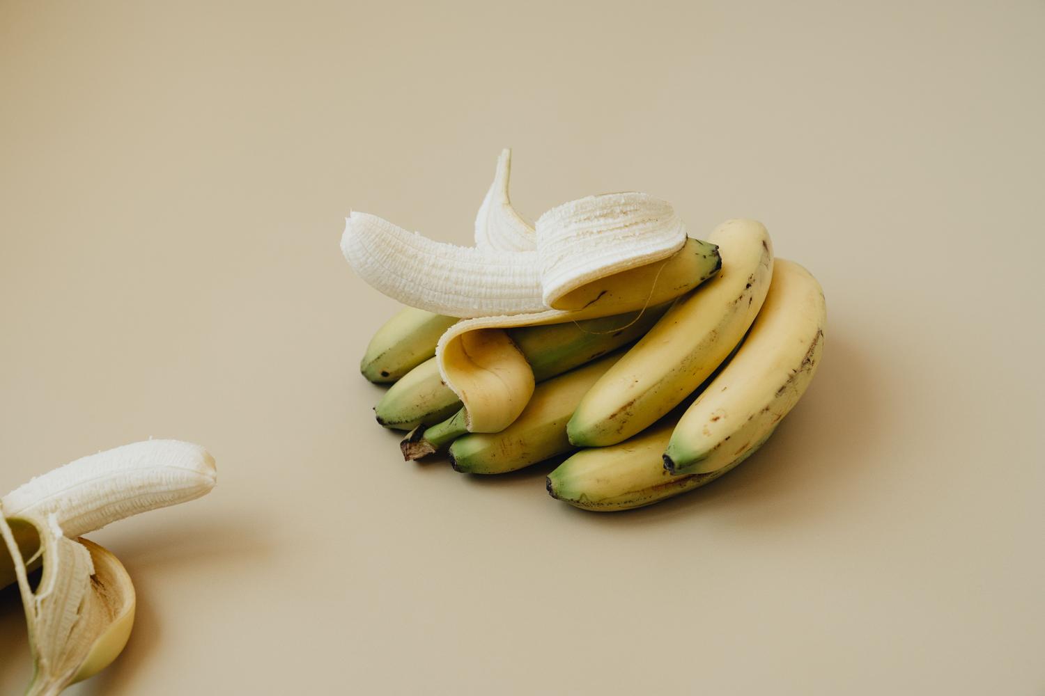 Plátanos maduros sobre un fondo neutro, alimentos ricos en potasio que ayudan a equilibrar el sodio en el cuerpo.
