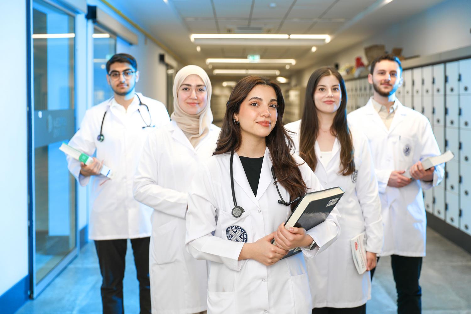Grupo de estudantes de medicina diversos no pasillo de uma universidade, representando a base académica e a diversidade na excelência médica.