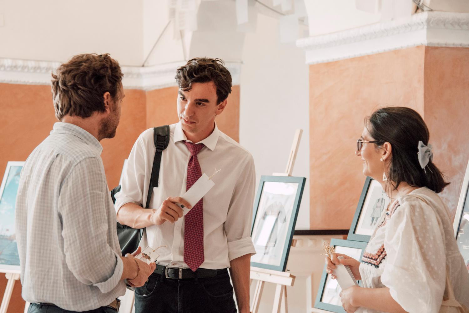 Conversación entre gestores culturales y potenciales donantes en una exposición de arte.