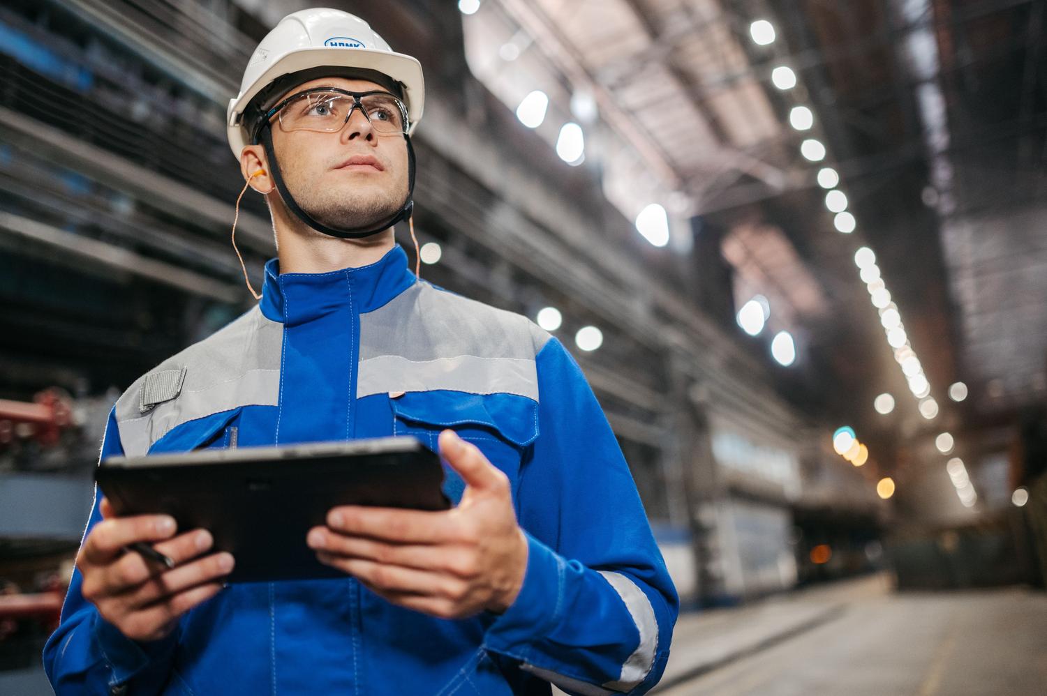 Operario industrial utilizando una tablet para la recolección y organización de datos en una planta de producción.