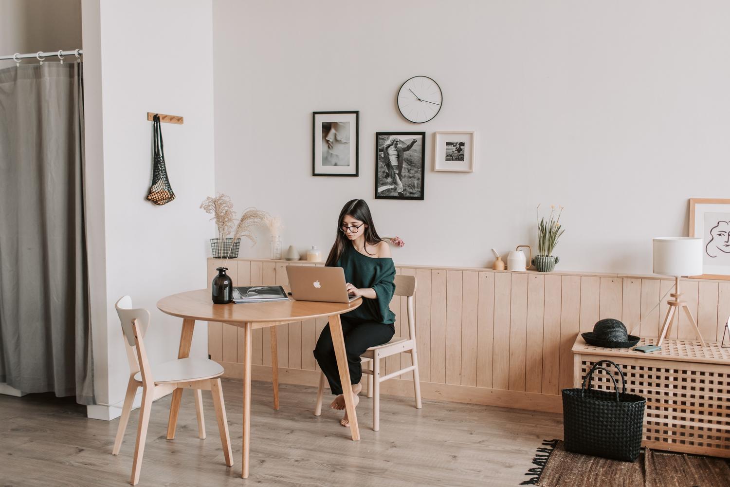 Mujer trabajando con su portátil en un salón moderno y espacioso, ilustrando el teletrabajo y el régime híbrido.