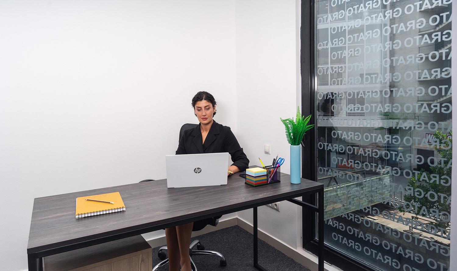 Mujer profesional concentrada en su trabajo en una oficina moderna, reflejando la adaptación al mundo digital y el uso de nuevas tecnologías.