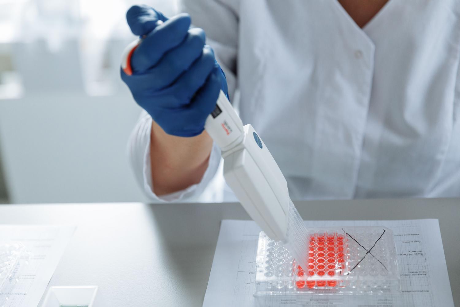 Investigador en un laboratorio utilizando una micropipeta para el análisis molecular y la búsqueda de estabilizadores proteicos.