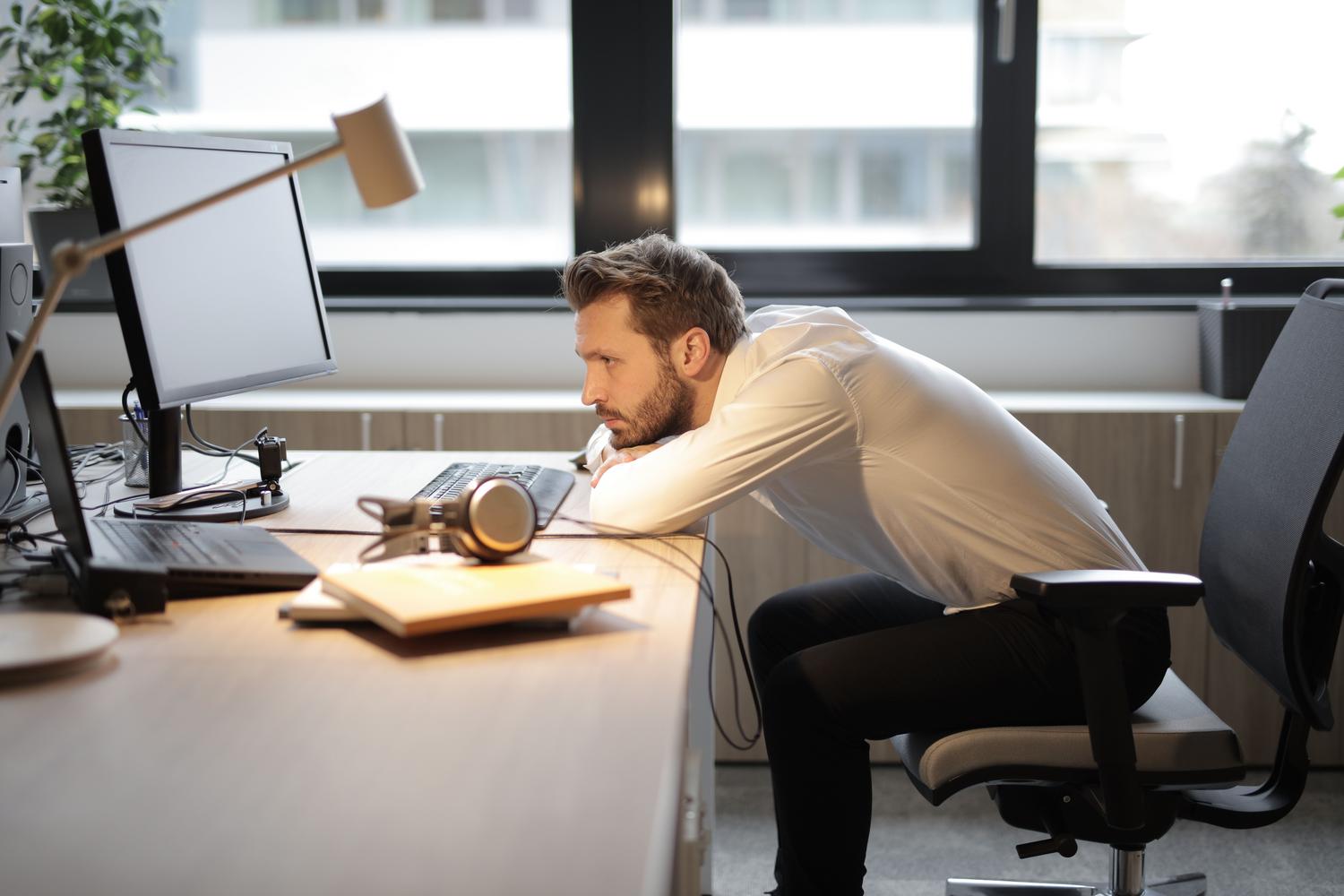 Hombre con mala postura frente al computador, encorvado y con tensión en el cuello