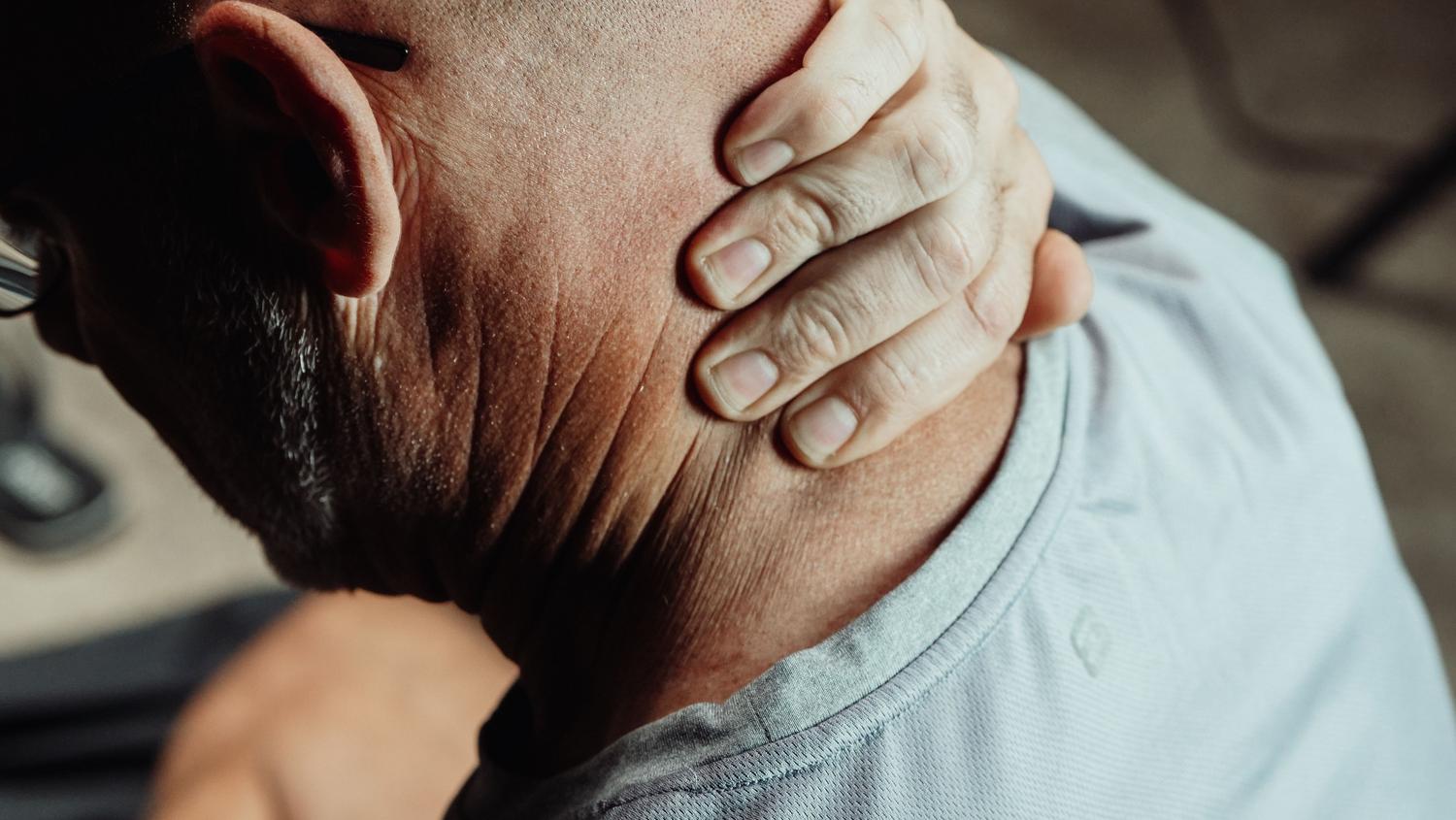Hombre con dolor de cuello reflejando tensión y estrés cervical