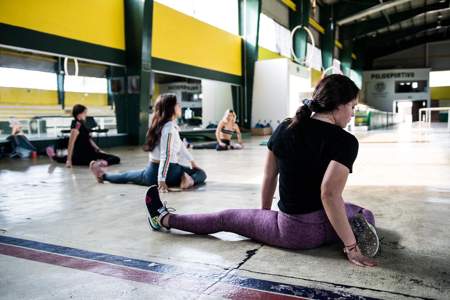 Mujeres realizando una sesión de estiramientos grupales en un gimnasio para prevenir lesiones.